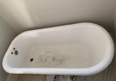 Bathtub surface before professional reglazing showing worn and stained finish